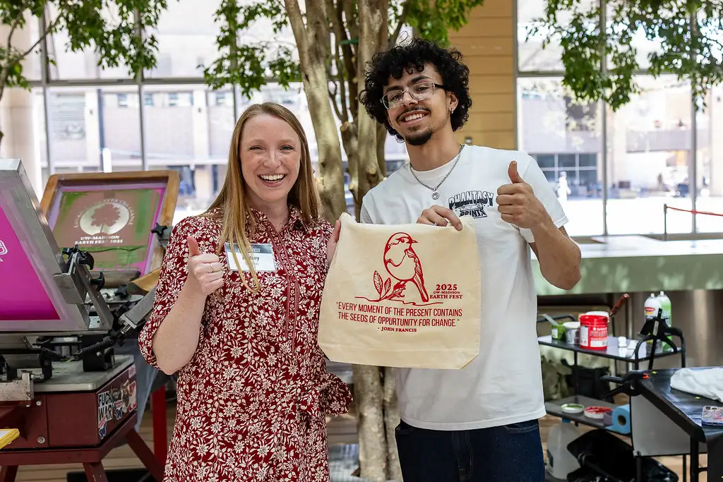 Two Earth Fest participants giving a thumbs-up while showing off a screen-printed tote bag.