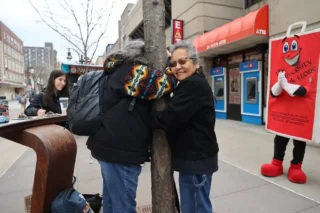 Two Earth Fest attendees hugging a tree on UW-Madison's Library Mall.