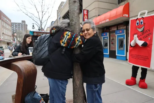 ef-13 Two Earth Fest attendees hugging a tree on UW-Madison's Library Mall.