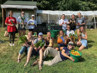 A group of UW-Madison students showing a variety of vegetables grown in a garden.