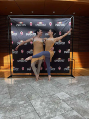 Two dancers from Kanopy Dance posing in front of the Earth Fest banner.